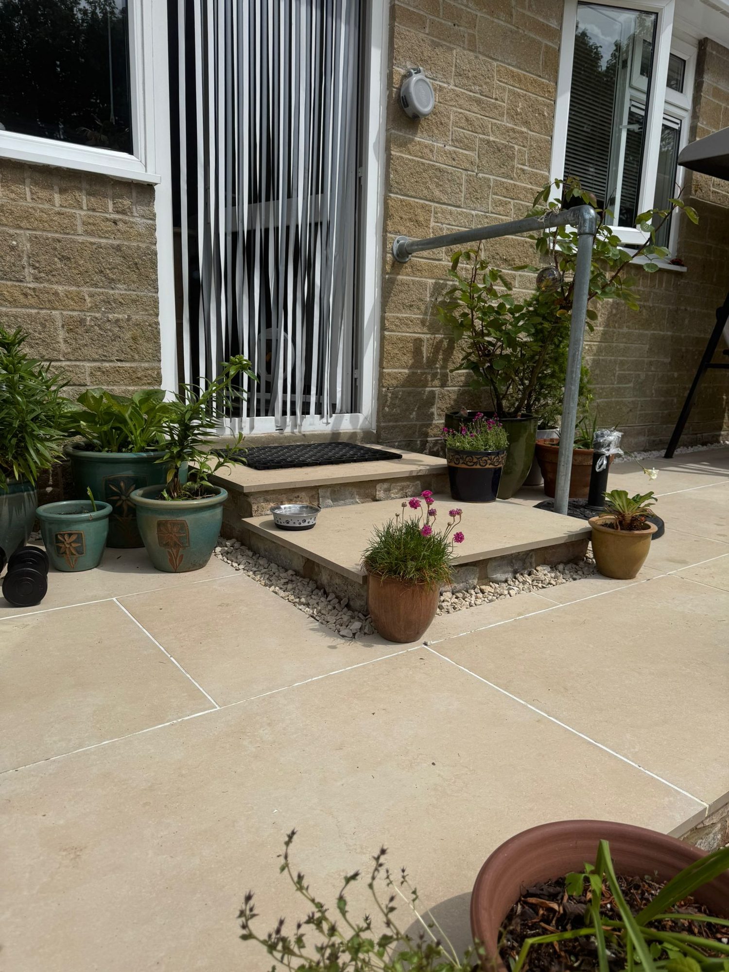 Sandstone patio and steps with planted pots outside a stone built house