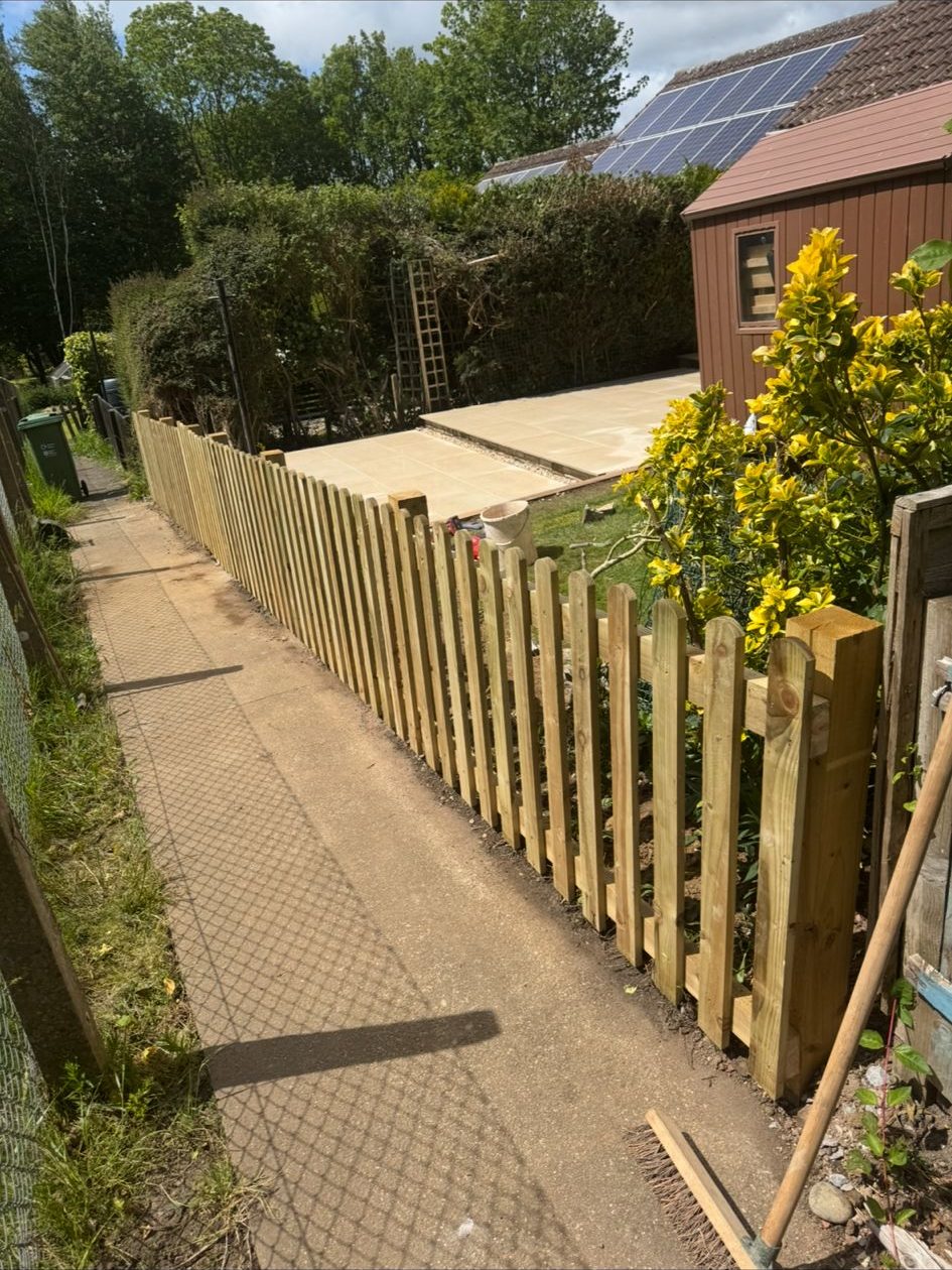 Low timber picket fencing enclosing a paved garden seating area