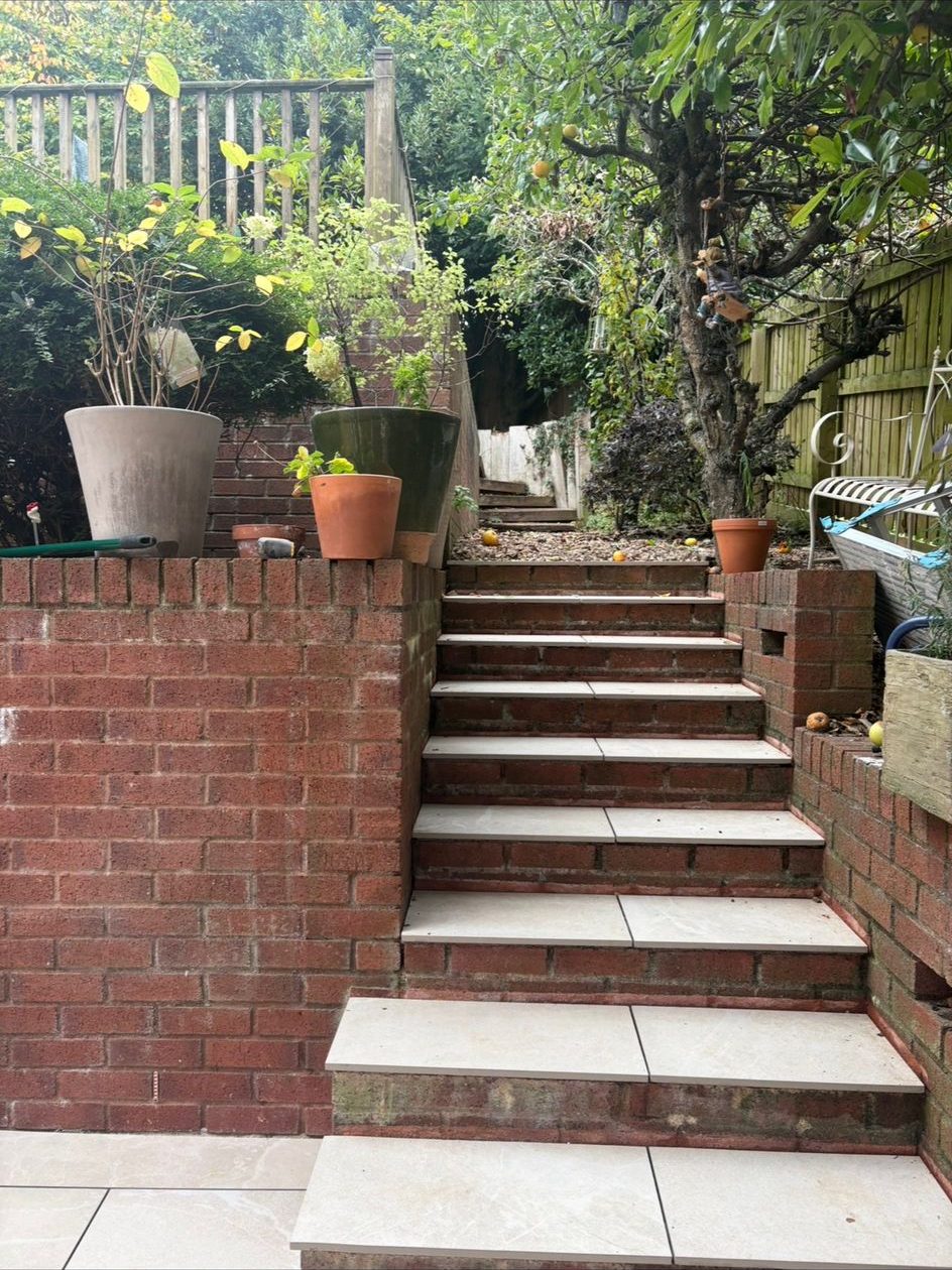 Paved garden steps with brick risers rising between raised brick walls
