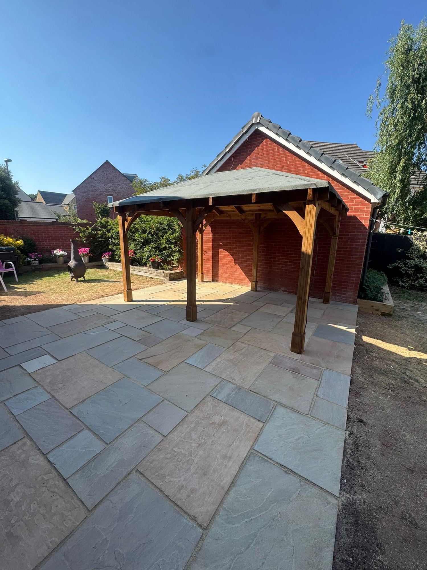 Oak framed garden shelter with felt roof over a new Indian sandstone patio
