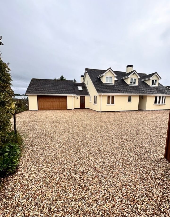 New gravel driveway laid in front of a large detached house and garage