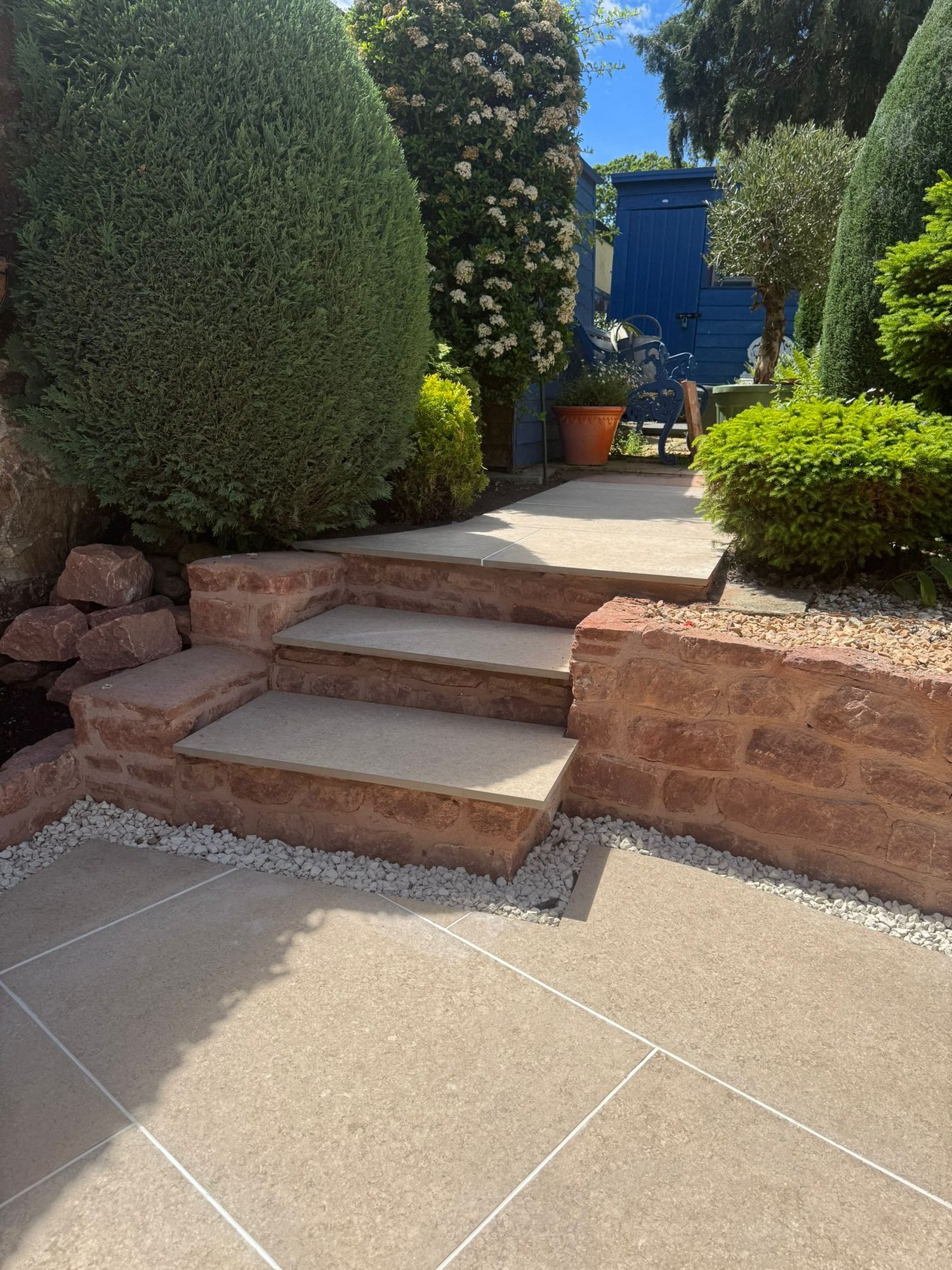 Red sandstone retaining walls and paved steps between two garden levels