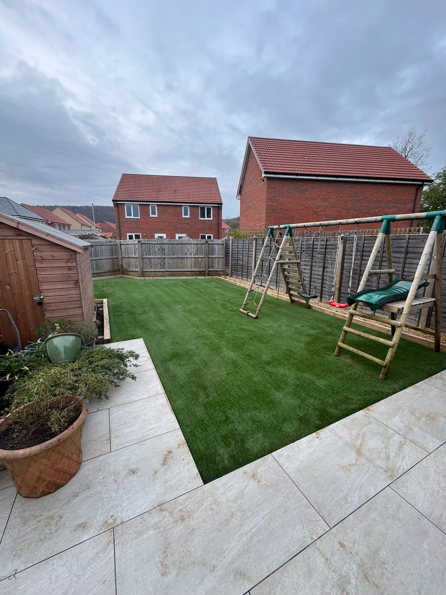 Freshly laid lawn bordered by porcelain paving in an enclosed family garden