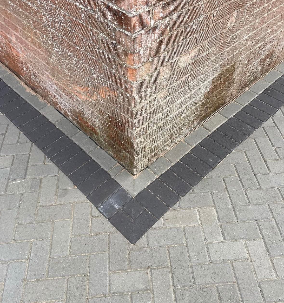 Grey block paved driveway with contrasting charcoal border course laid around a brick corner