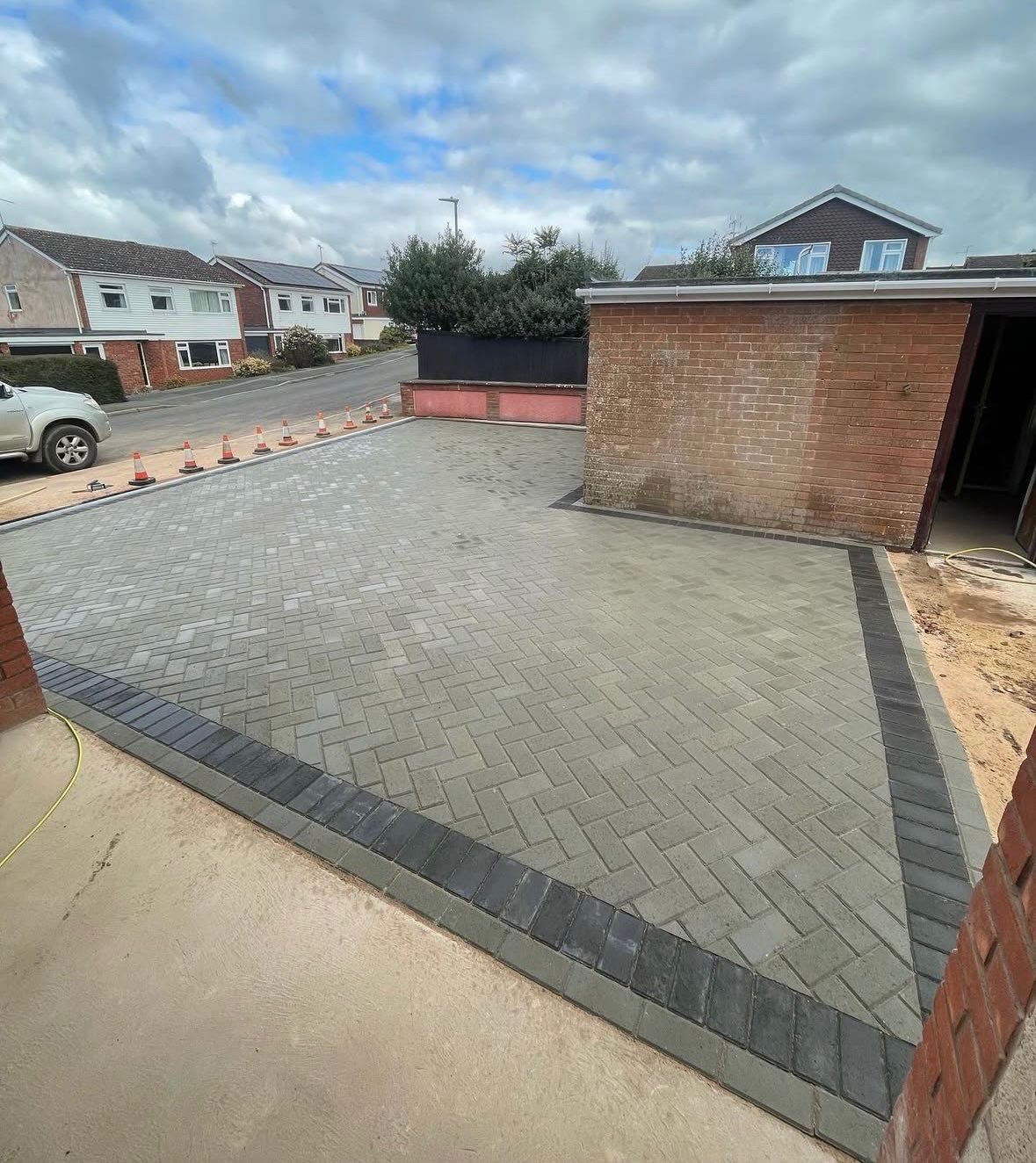 Completed block paved driveway with dark edging beside a domestic garage