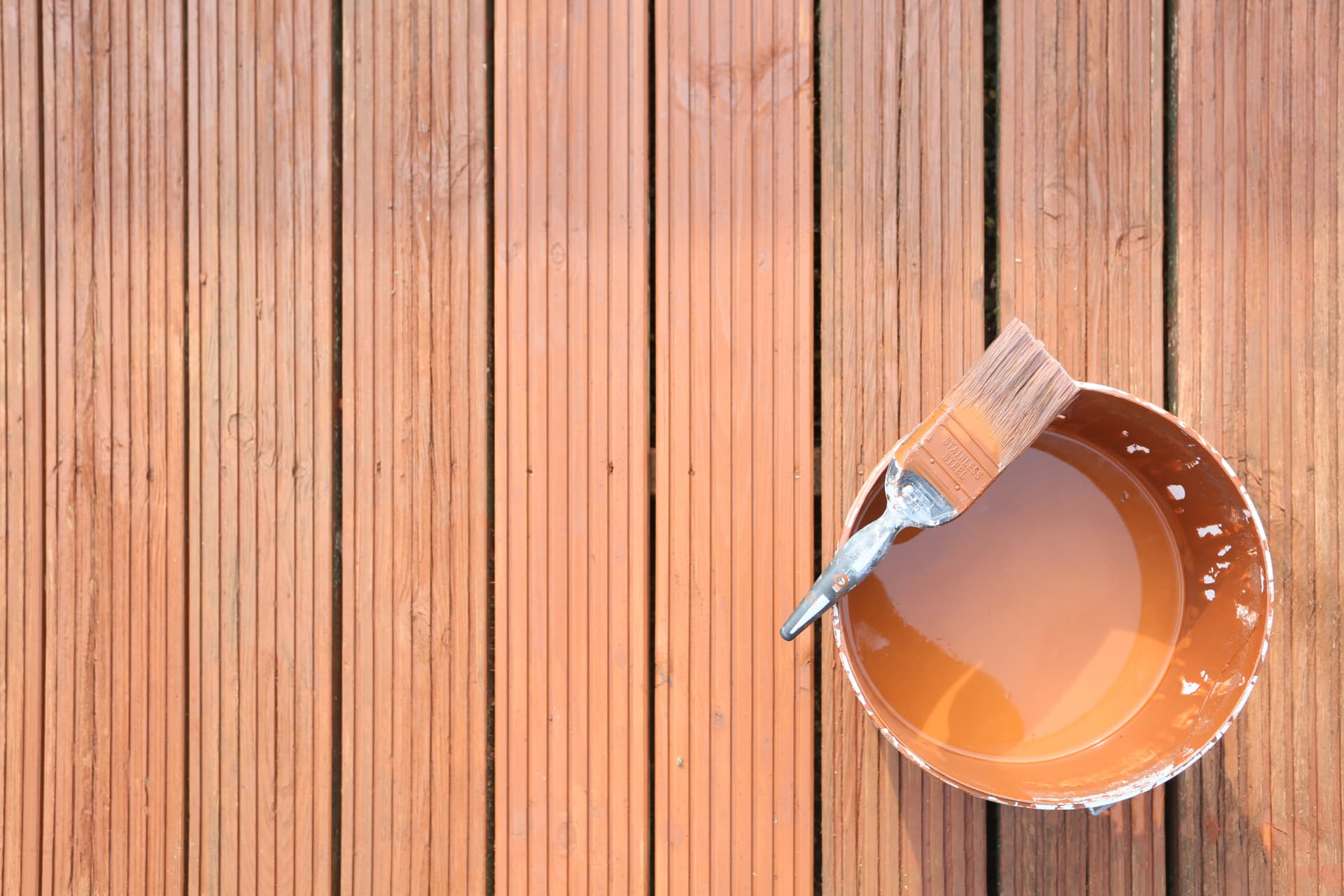 Timber decking boards being treated with protective decking stain